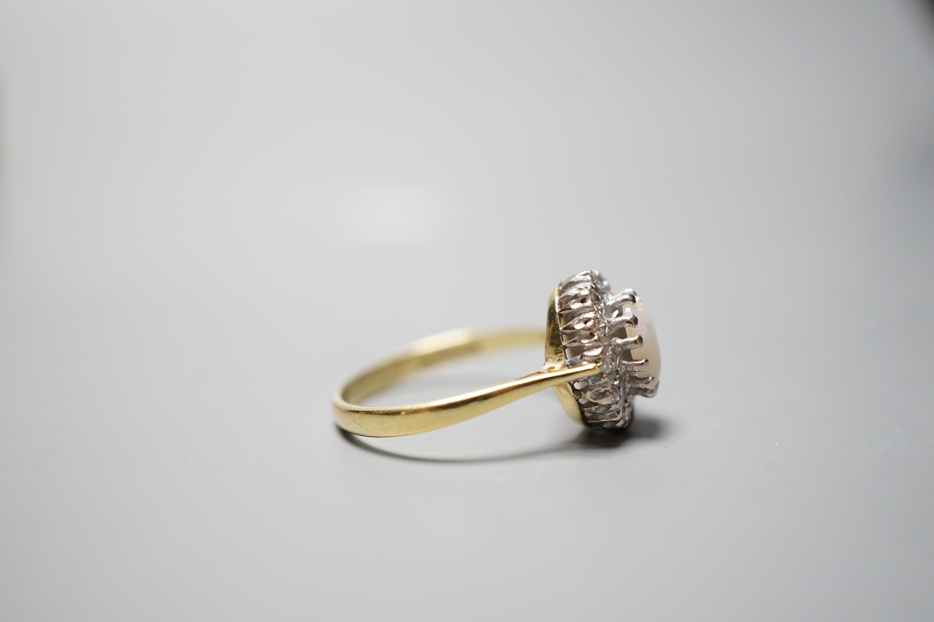 A modern 18ct gold, white opal and diamond chip set oval cluster ring, size N, gross weight 3.6 grams.